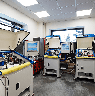 Nowoczesny warsztat wyposażony w liczne skomputeryzowane stanowiska do testowania i kalibracji komponentów motoryzacyjnych.