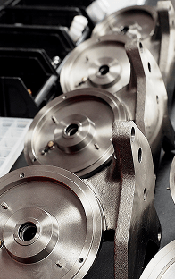 Zbliżenie na różne precyzyjnie obrobione komponenty metalowe na stole warsztatowym w fabryce, z pojemnikami na mniejsze części gotowe do montażu.